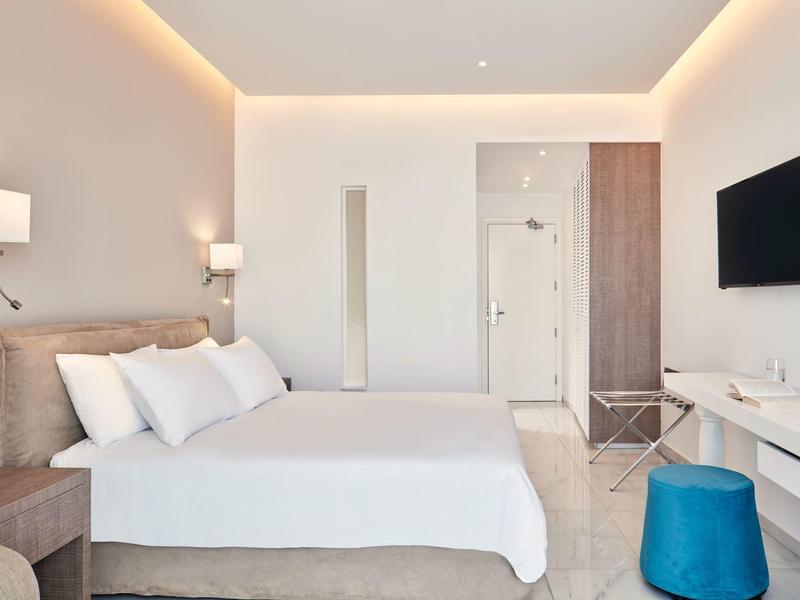 Helles, modernes Schlafzimmer mit großem Bett, weißen Wänden und minimaler Dekoration.