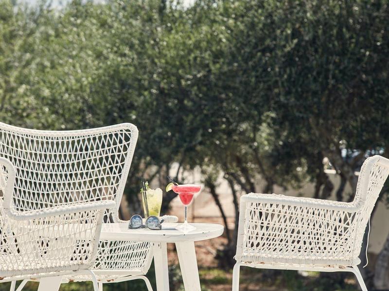 Weißes Gartenmöbelset mit Getränken, umgeben von Bäumen im Freien.