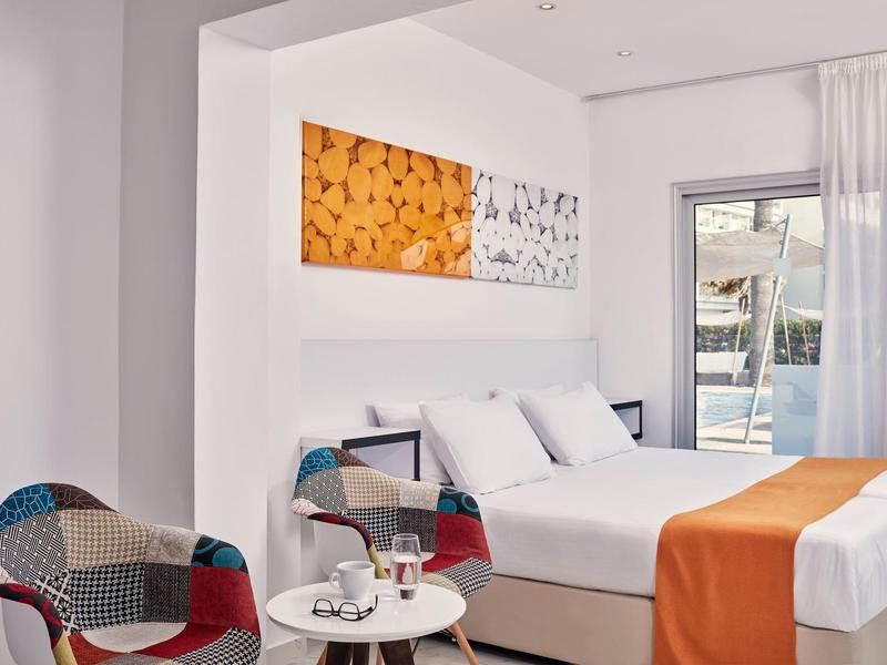 Modern eingerichtetes Hotelzimmer mit Doppelbett und buntem Sessel.