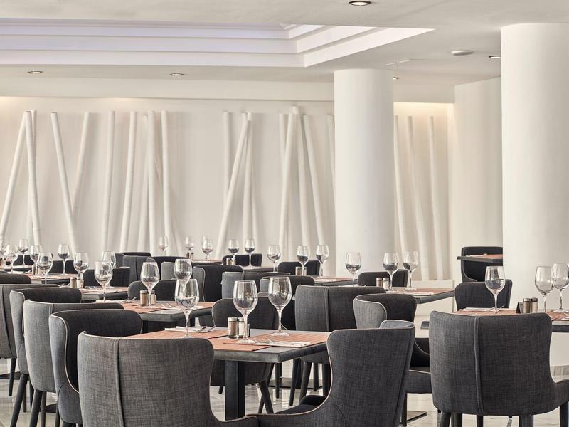 Modernes Restaurant mit dunklen Stühlen, Holztischen und weißen Wänden mit vertikalen Falten.