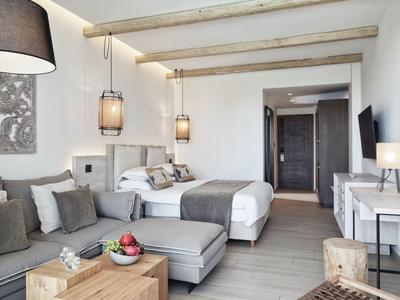 Gemütliches Hotelzimmer mit grauer Couch, Doppelbett, Holzmöbeln und modernem Design.
