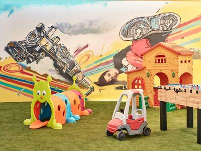 Bunter Spielraum mit Roboter-Wandkunst, Kletterraupe, Spielzeugauto und Tischfußballspiel.