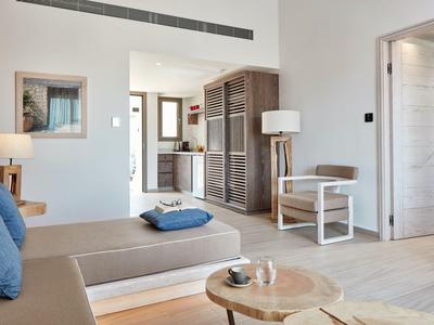 Helles Wohnzimmer mit Holzmöbeln, beigem Sofa und blauen Kissen, offen zum angrenzenden Raum.