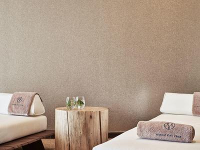 Zwei weiße Betten mit braunen Handtüchern, zwischen ihnen ein rustikaler Holztisch mit Gläsern.