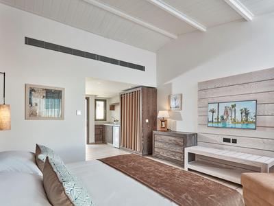 Chambre d'hôtel moderne avec lit double, commode, tapis et fenêtre donnant sur des arbres.