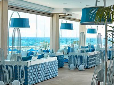 Restaurant moderne avec décoration bleue et blanche et vue sur la mer par de grandes fenêtres