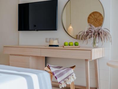 Moderner Tisch mit hellem Holz, Spiegel, TV und einem Stuhl mit Decke in einem hellen Raum.