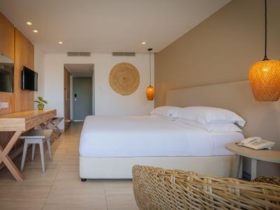 Modernes Hotelzimmer mit Doppelbett, Holzmöbeln und warmem Licht.