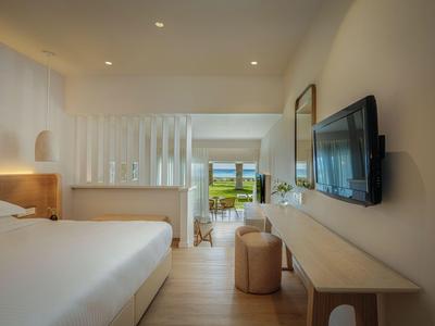 Modernes Hotelzimmer mit großem Bett, Fernseher an der Wand und Blick auf die Terrasse.