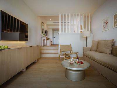 Modern eingerichtetes Wohnzimmer mit Sofa, Sessel, Couchtisch und TV in einem hellen Raum.