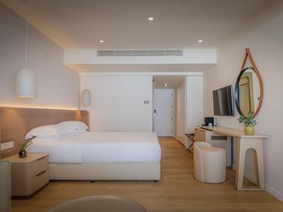 Modern eingerichtetes Hotelzimmer mit Doppelbett, Holzfußboden und hellem Design.