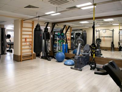 Palestra luminosa con attrezzature moderne, sacco da boxe e palle da ginnastica su pavimento chiaro.