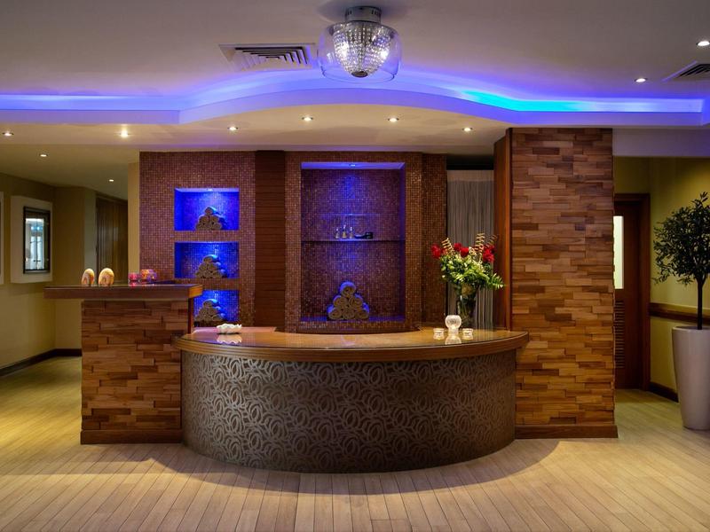 Moderne Rezeption mit rundem Empfangstresen, blauer LED-Beleuchtung und dekorativen Pflanzen.