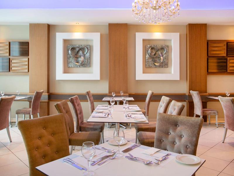 Modernes Restaurant mit bequemen Polstersesseln, gedeckten Tischen und stilvoller Wanddekoration.