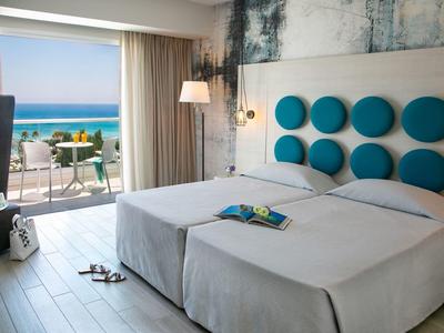 Helles Schlafzimmer mit zwei Betten, runden blauen Wanddekorationen und Blick auf das Meer.