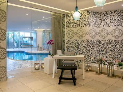 Elegante area benessere con tavolo, sedia e vista su una vasca idromassaggio sullo sfondo.