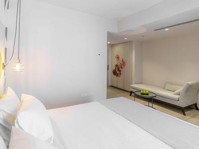 Modern eingerichtetes Hotelzimmer mit großem Bett, Sofas und minimalistischem Design.