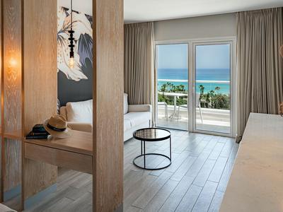 Helles Hotelzimmer mit großem Fenster, Meerblick und modernem, minimalistischem Interieur.
