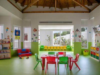Heller Kindergartenraum mit bunten Möbeln und Blick auf einen Garten.