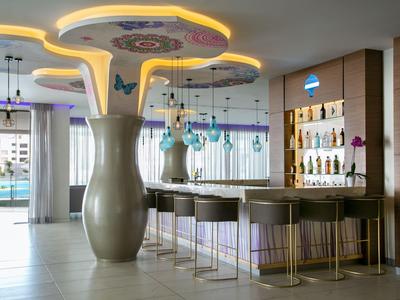 Moderner Hotelbarbereich mit futuristischen Deckenleuchten und stilvollen Barhockern.