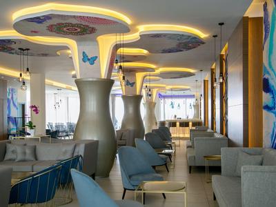 Modern eingerichtete Hotellounge mit leuchtenden Deckenakzenten und komfortablen Sitzmöbeln.