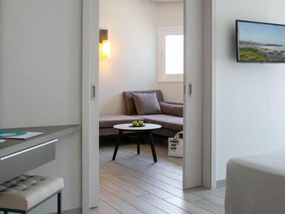 Moderner Hotelraum mit offenem Schiebetürzugang zu einem Wohnzimmer mit Sofa und Tisch.