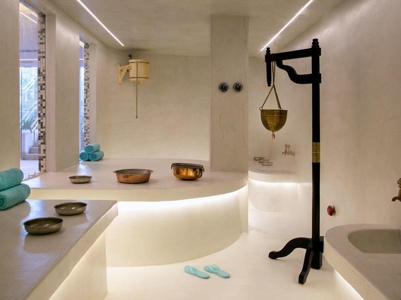Moderner Spa-Raum mit weißen Wänden, Ruhebereich, Becken und minimalistischem Design.