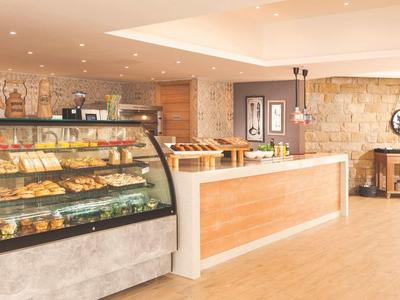 Innenraum einer hellen Bäckerei mit Glasvitrine voller Backwaren und langem Verkaufstresen.