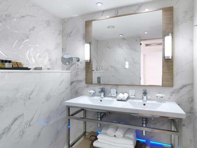 Modernes Badezimmer mit doppeltem Waschbecken, großem Spiegel und Marmorwänden.