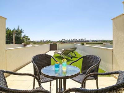 Terrasse mit rundem Glastisch, vier Stühlen, Sonnenschirmen und Blick auf grünen Garten.