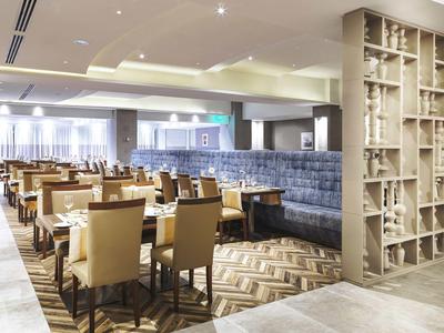 Moderner Hotel-Speisesaal mit Tischen, Stühlen und einer gepolsterten Wand