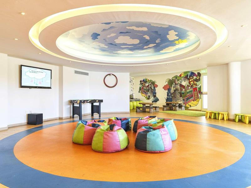 Bunter, runder Sitzbereich mit Kissen auf orange-blauem Boden unter dekorativer Decke.