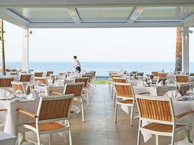 Elegancka restauracja na świeżym powietrzu z widokiem na morze i białymi obrusami.