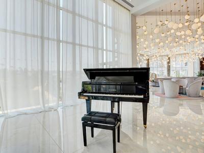 Schwarzer Flügel mit passendem Klavierhocker in hellem, modernem Raum mit großen Fensterfronten.
