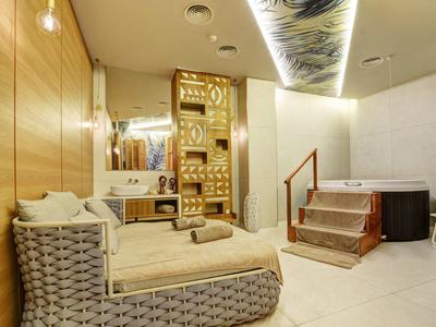 Moderne Wellnesslounge mit hellen Holzwänden, bequemen Liegen und dekorativer indirekter Beleuchtung.