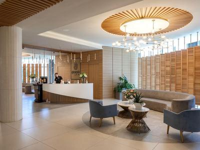 Hall d'hôtel moderne avec réception, espace salon et accents décoratifs en bois.