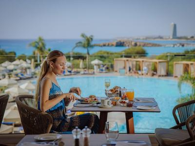Femme assise à une table dressée près de la piscine avec vue sur la mer à l'hôtel.