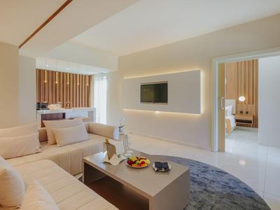 Chambre d'hôtel moderne avec canapé, télévision et décoration élégante aux couleurs neutres.