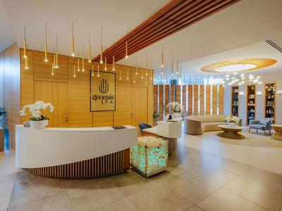 Lobby d'hôtel moderne avec comptoir d'accueil rond, éclairage chaleureux et éléments décoratifs.