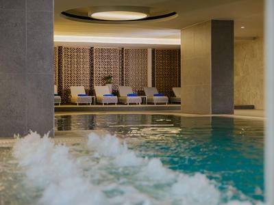 Piscine intérieure avec eau bouillonnante et espace lounge dans un hôtel.