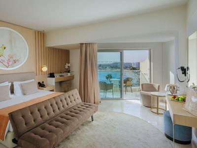 Chambre d'hôtel moderne avec lit double, canapé, balcon et vue sur la mer