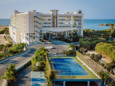 Hôtel moderne en bord de mer avec piscine et allée courbée.