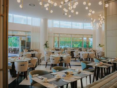 Restaurant élégant avec des chaises blanches, de grandes fenêtres et un éclairage moderne au plafond.