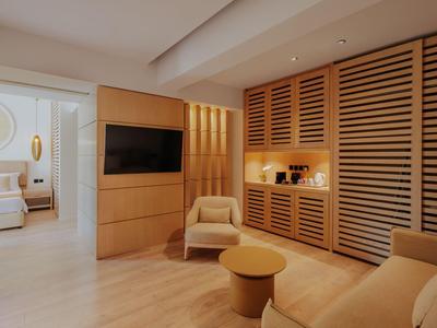 Chambre d'hôtel moderne avec meubles en bois clair et coin salon confortable.