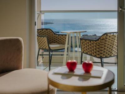 Vue depuis une chambre avec table et deux chaises sur un balcon avec vue sur la mer.