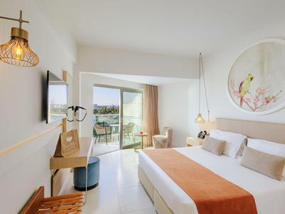 Chambre d'hôtel moderne avec grand lit, balcon et vue sur la mer.