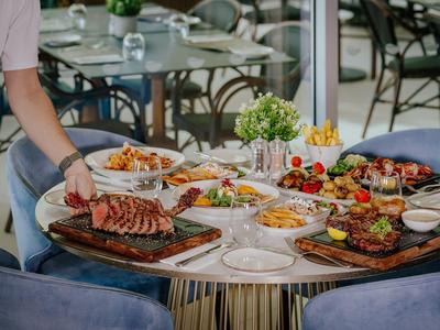 Une table dressée avec divers plats et une personne servant un steak.
