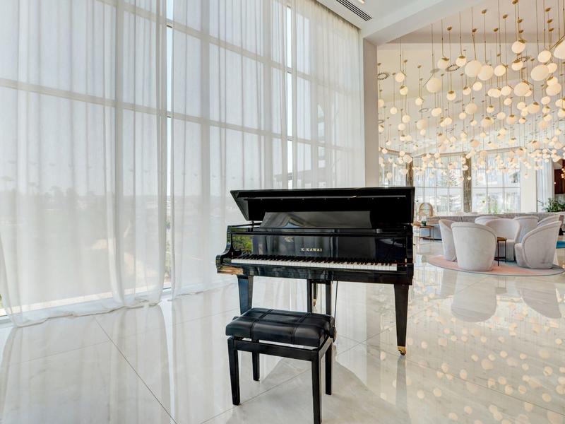 Schwarzer Flügel mit passendem Klavierhocker in hellem, modernem Raum mit großen Fensterfronten.