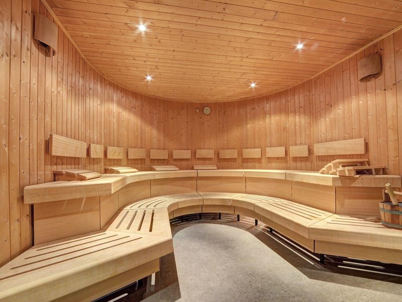 Sauna mit gebogenem Holz-Sitzbereich, Holzverkleidung und sanfter Deckenbeleuchtung.