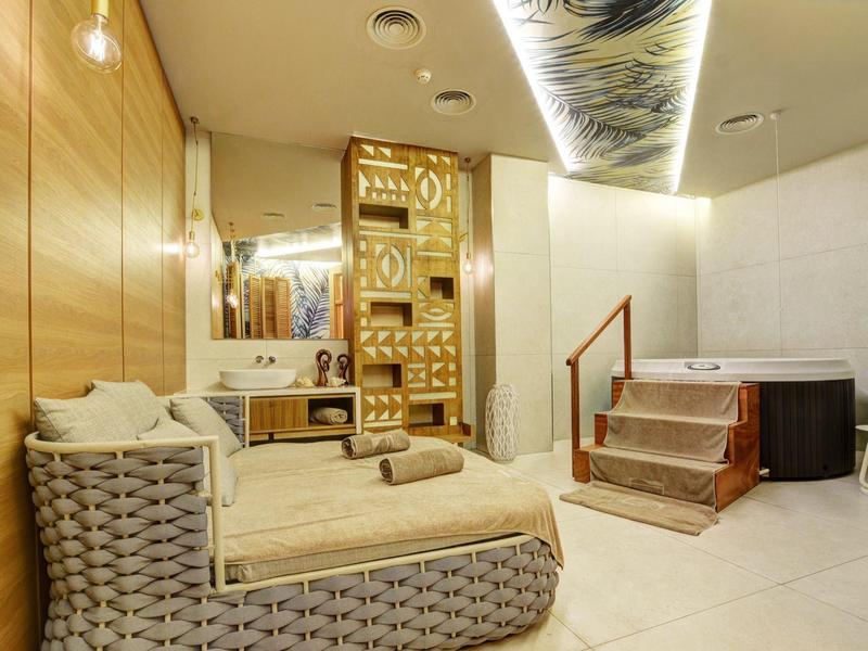 Moderne Wellnesslounge mit hellen Holzwänden, bequemen Liegen und dekorativer indirekter Beleuchtung.